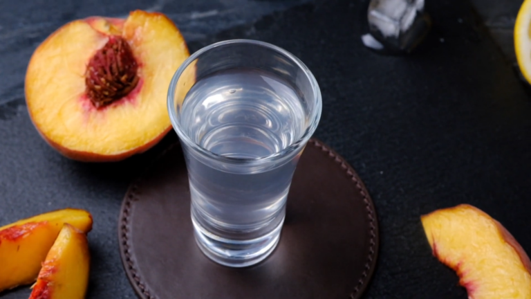 A Close-Up of A White Tea Shot Served in A Glass, Accompanied by Fresh Peach Slices