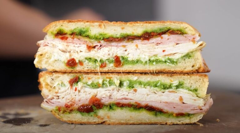 A layered panini, showcasing slices of roasted turkey, ham, and melted cheese