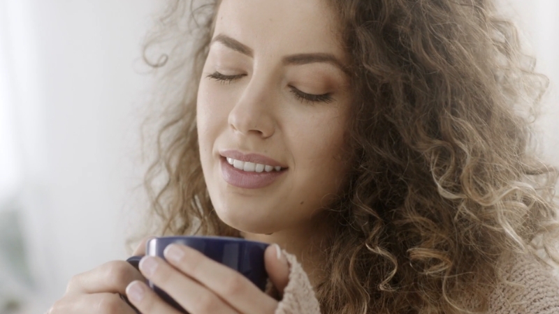 A woman holding a cup, showing the trend of mixing apple cider vinegar with coffee and its dental risks