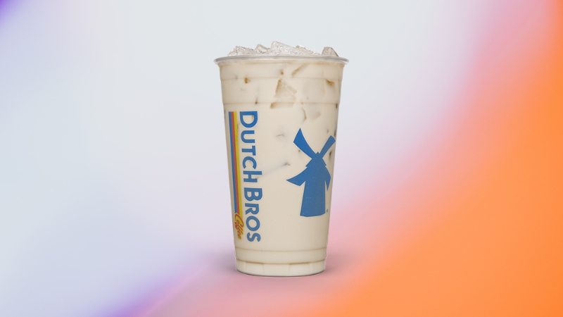 A large iced White Zombie drink from Dutch Bros sits against a soft gradient background