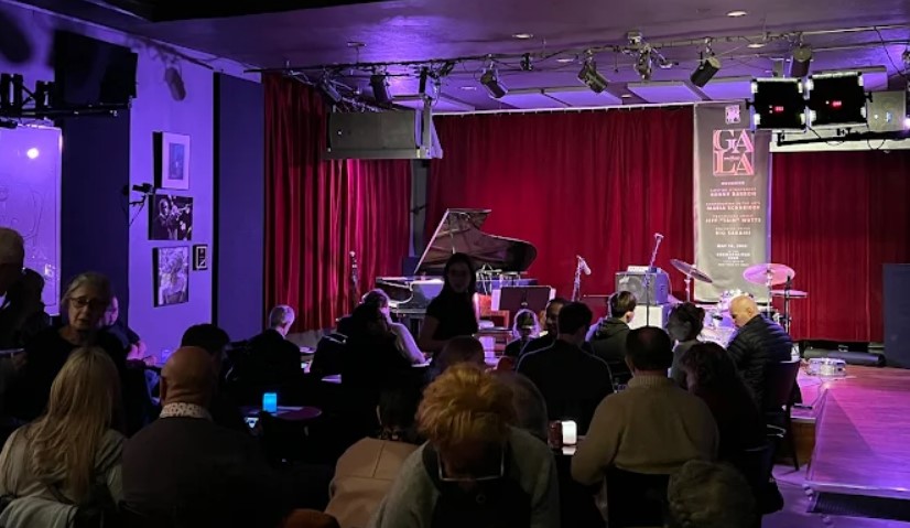 A jazz club, bathed in warm light, filled with the anticipation of live music