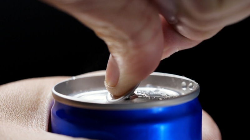 A person opens a blue can of energy drink