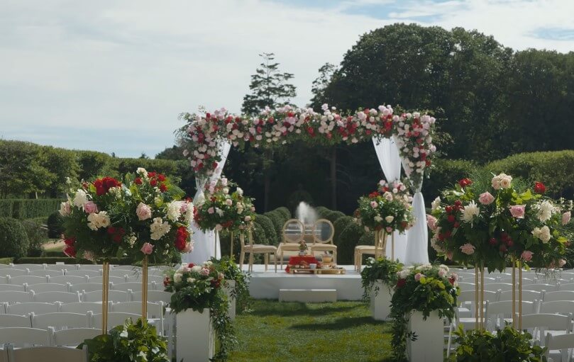 A breathtaking floral archway, draped in white, frames a ceremony bathed in the soft sunlight