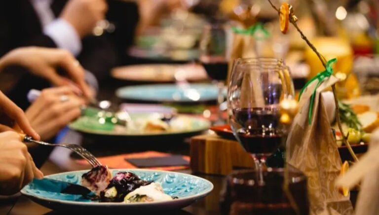 People dining at a restaurant, enjoying meals with wine glasses and plates on the table