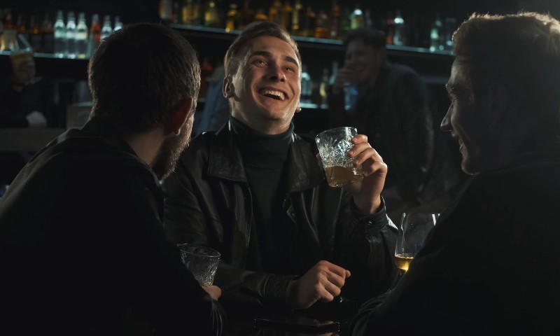 Three men sitting at a bar, laughing together
