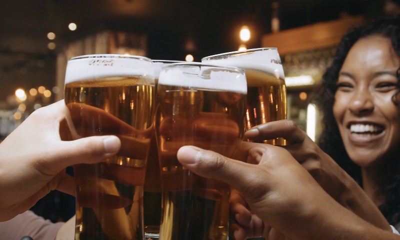 A group of diverse people joyfully toasting with beer glasses in a festive setting