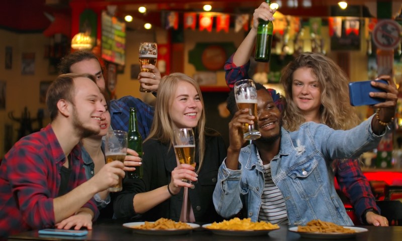 A group of people laughing and enjoying drinks at a lively bar