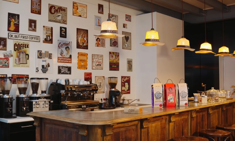 Warm, cozy coffee shop with vintage decor; wall lined with retro coffee signs