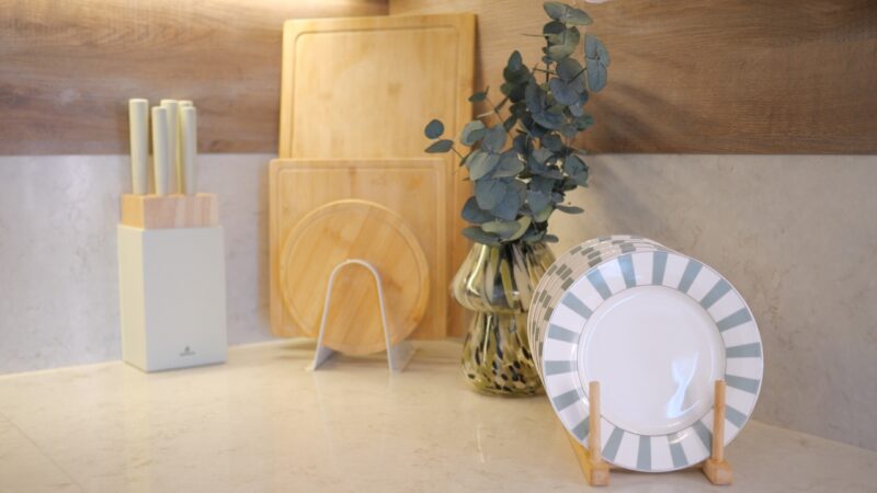 Wooden cutting boards, knife block, plates, and a plant add warmth to a clean kitchen counter